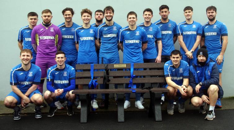 Hakin United squad surround the memorial bench for Alan Roach at the Obs
